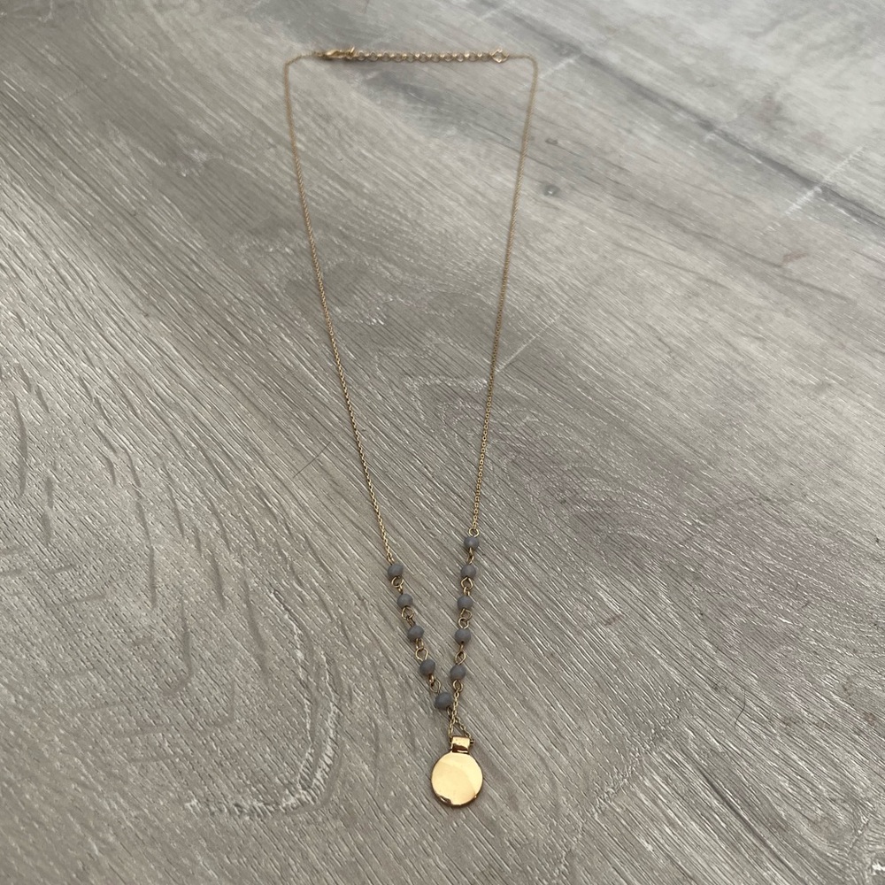 Gold necklace with gray beads and gold disc/pendant.